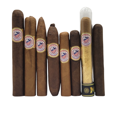 The Premium Sampler Pack features nine cigars of different sizes and shades, each with a patriotic badge label. One cigar is displayed in a clear tube with a gold wrapper, all arranged against a white background.