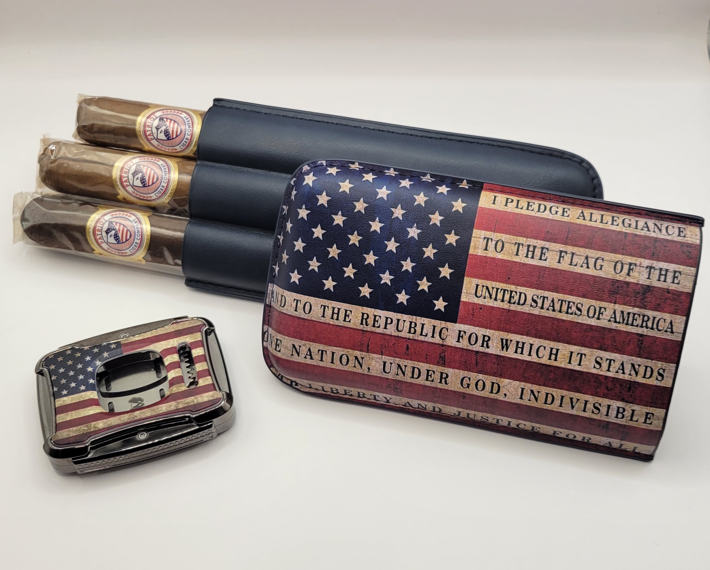 The PATRIOT PACK features a cigar case, cutter, and three cigars with American flag designs and the Pledge of Allegiance text, all displayed on a white surface.