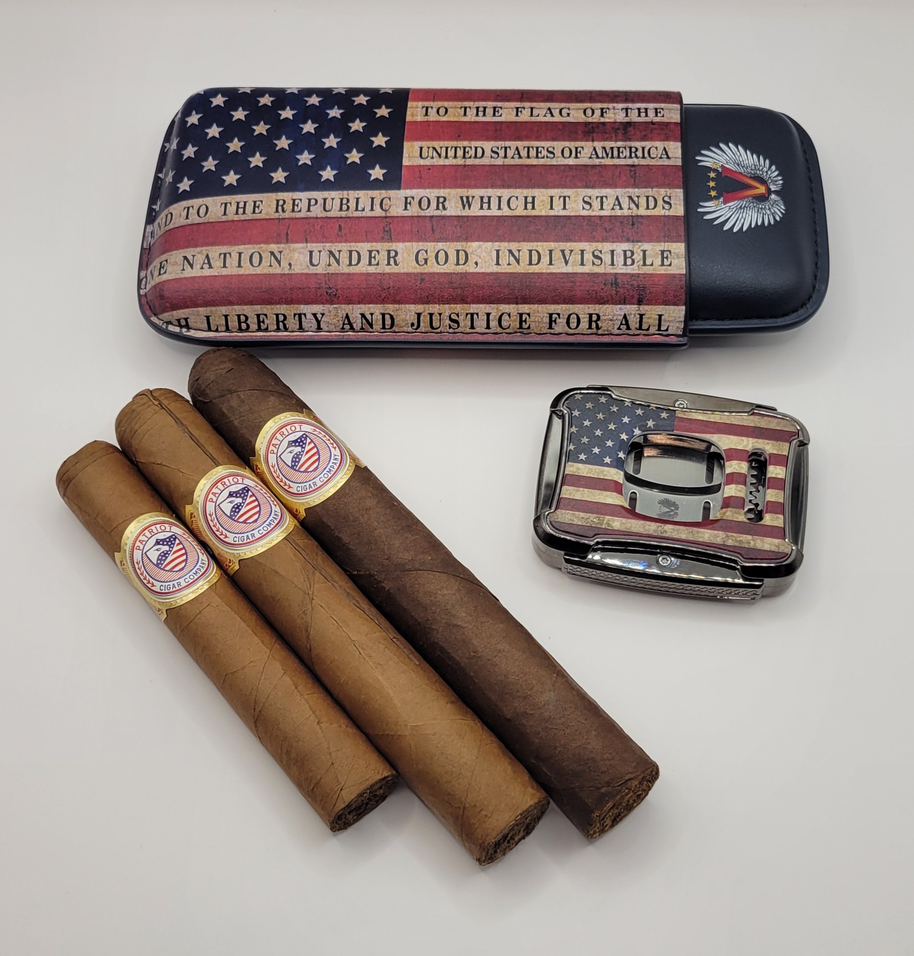 The PATRIOT PACK, featuring three cigars, a cigar case, and a cigar cutter with American flag designs and patriotic text, is arranged on a white background.