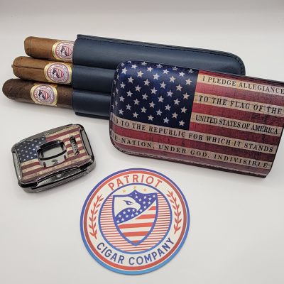 The PATRIOT PACK includes three cigars, a lighter, a cigar case, and a round sticker, all featuring American flag designs and "Patriot Cigar Company" branding, displayed on a white background.